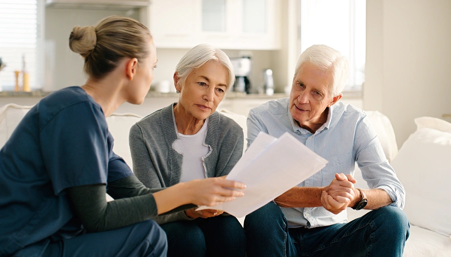 Healthcare professional discussing documents with elderly couple.