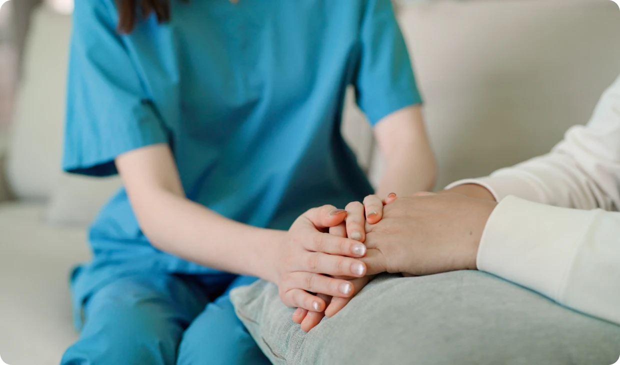 Nurse comforting patient with gentle hand touch.