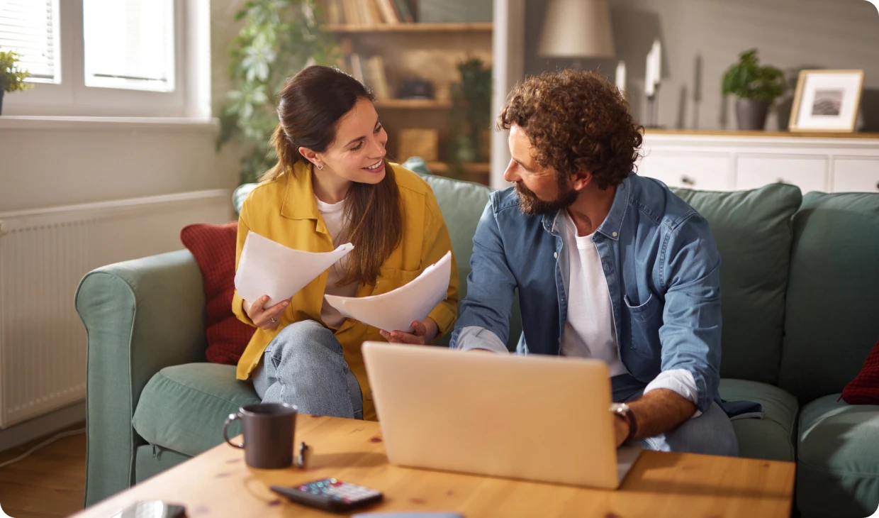 Couple discussing paperwork on a couch.