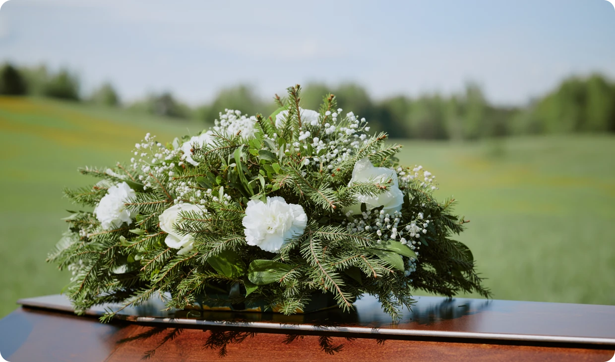 Floral arrangement on casket in peaceful field.