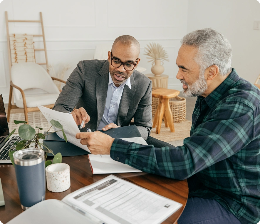 Two men discussing documents at table.